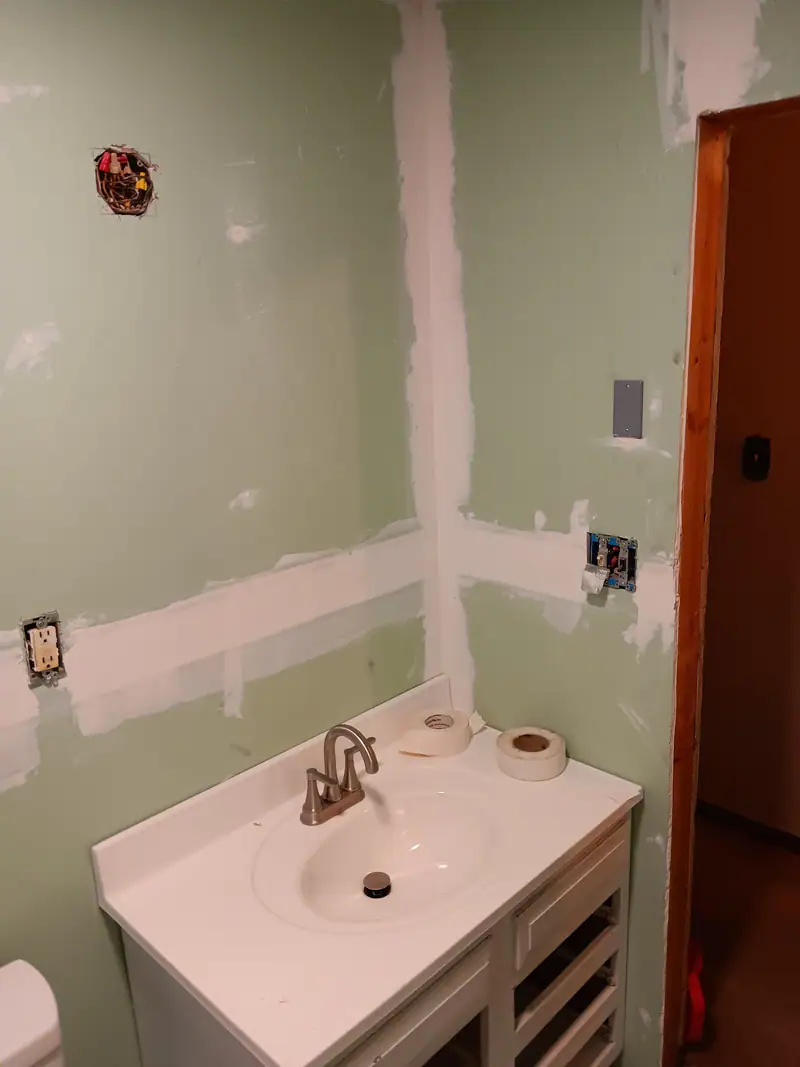 Bathroom with drywall patches mudded and a new vanity in place