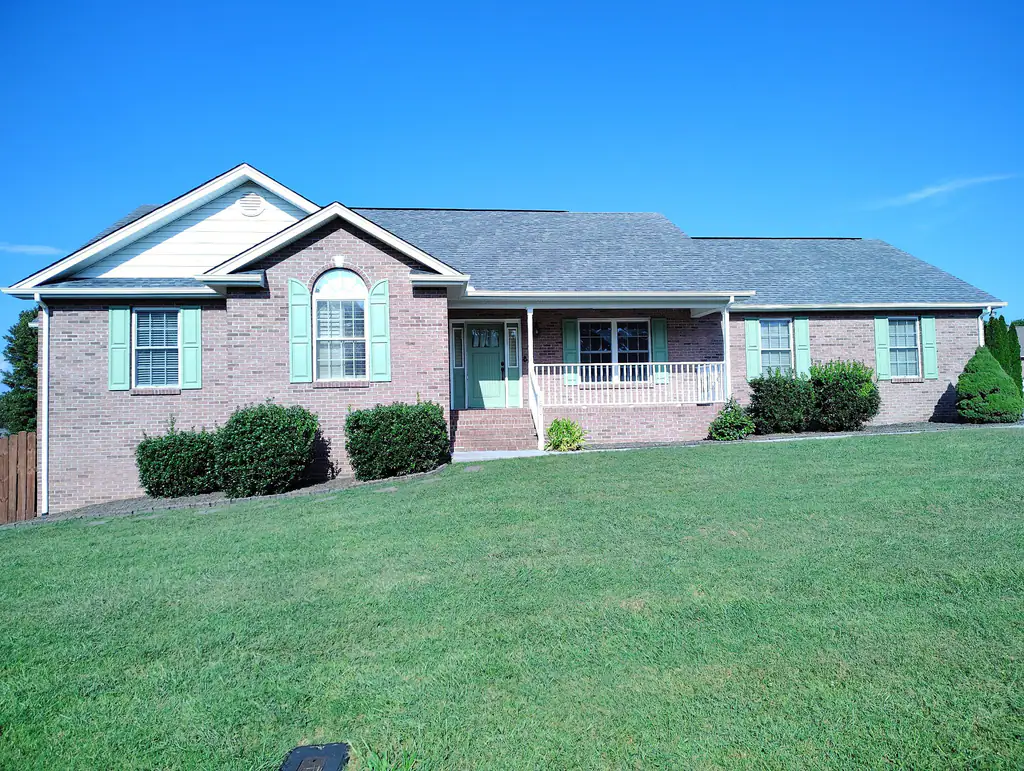 Brick ranch home with green shutters and a wide front lawn