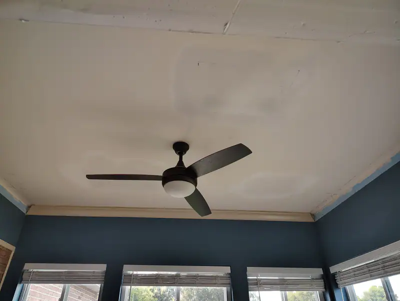 Smooth new ceiling with a black ceiling fan in a sunroom