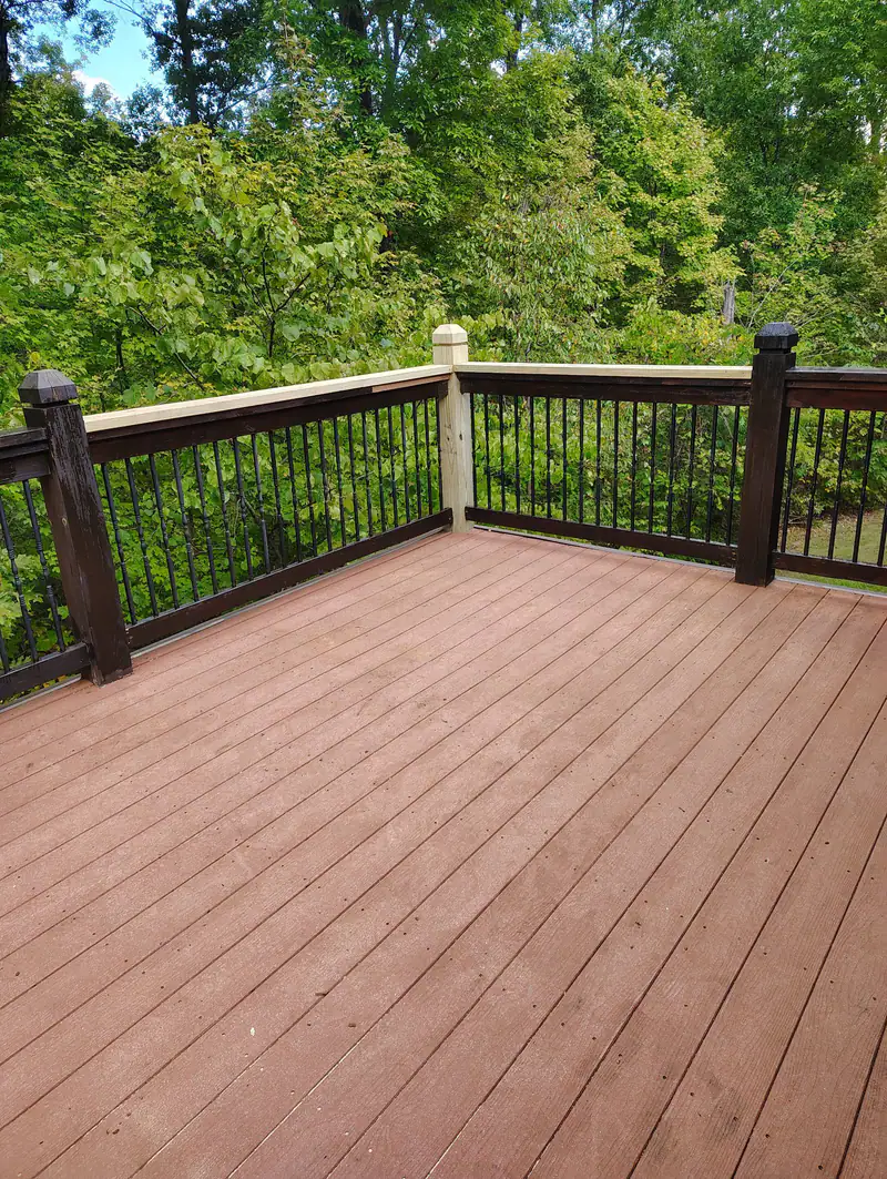 Deck with dark stained railings and black balusters above a wooded yard