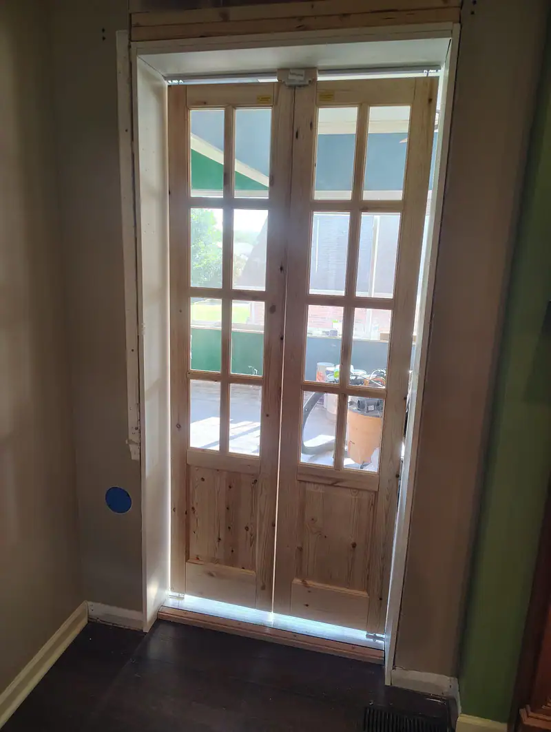 Pine French doors trimmed out in a sunroom doorway