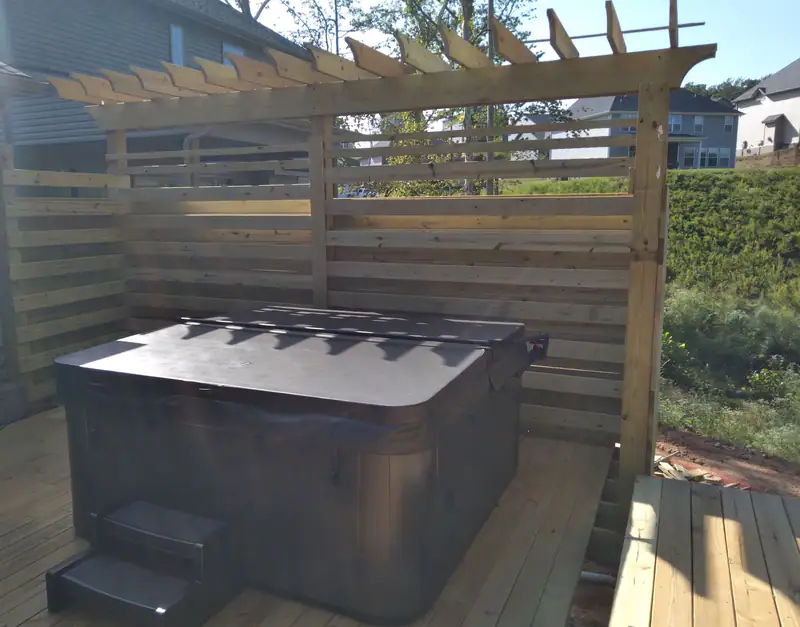 Horizontal-slat privacy screen and pergola built around a hot tub on a new deck
