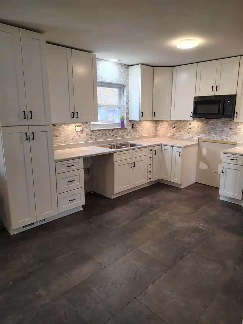 Finished kitchen with white cabinets and a dark tile floor