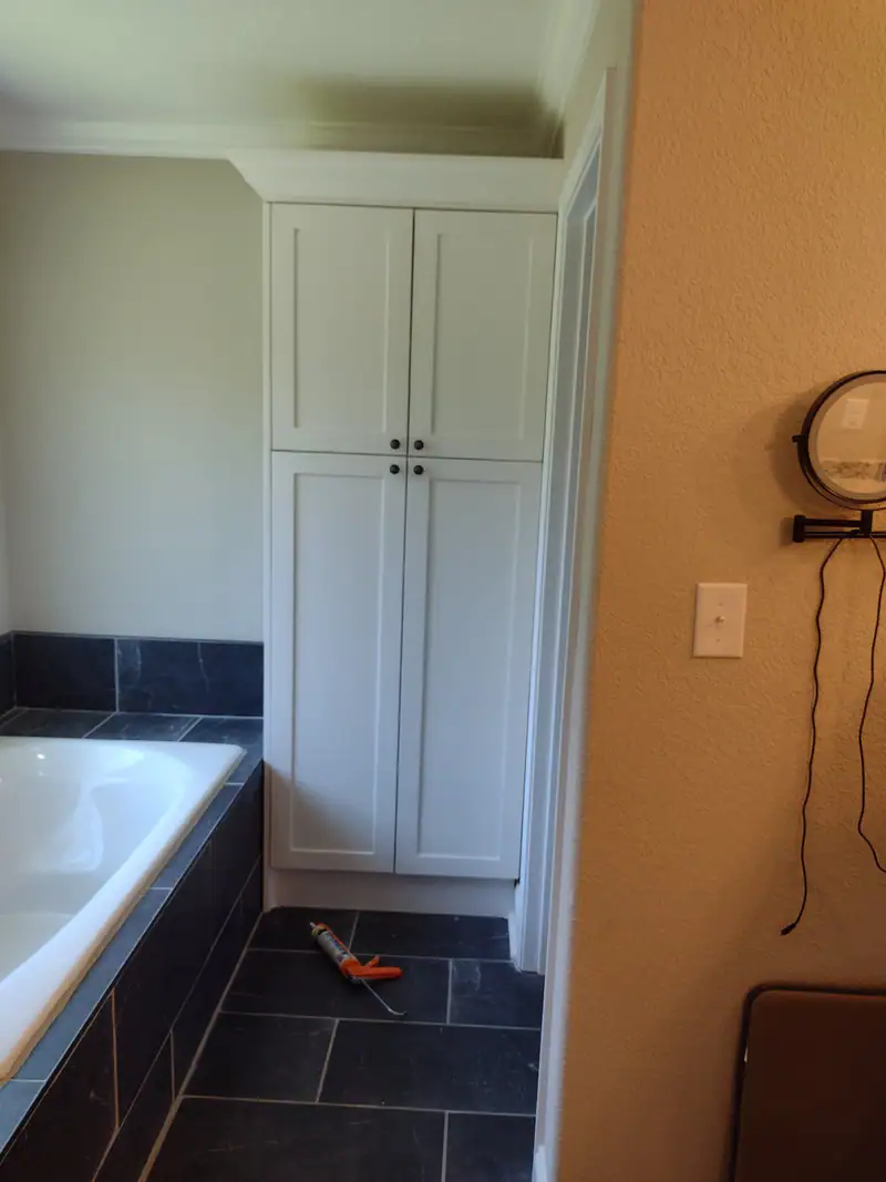 Built-in linen cabinet beside a soaking tub