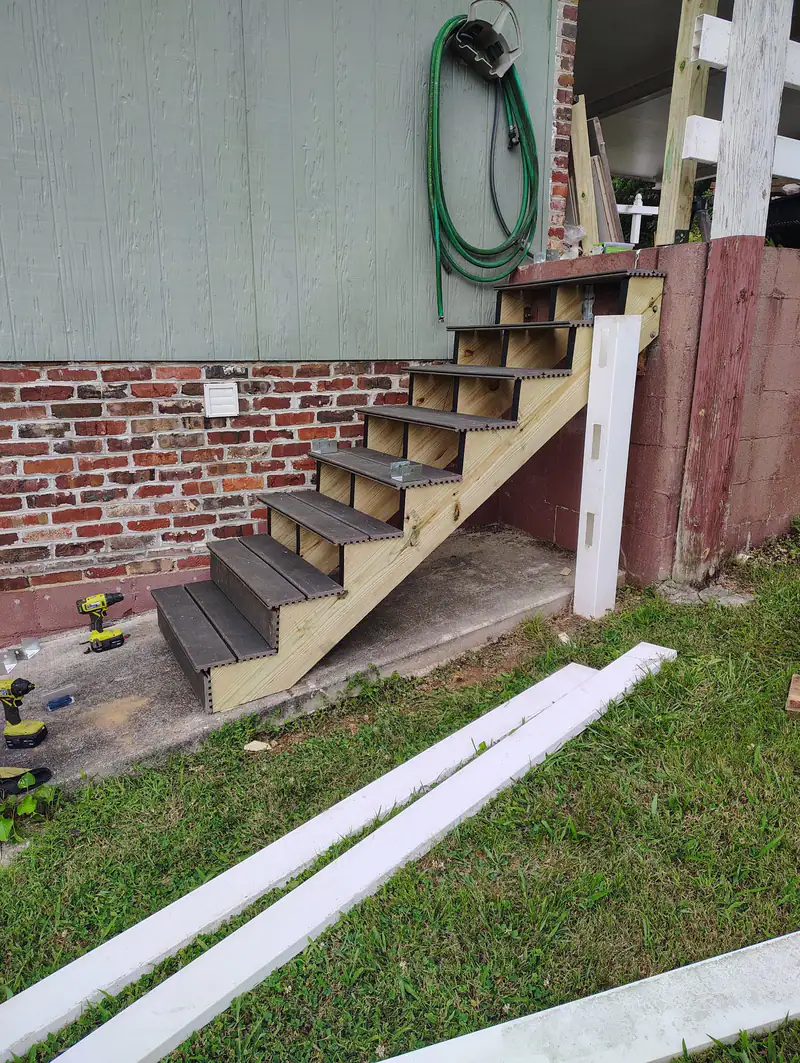 New stair treads going in beside a brick foundation