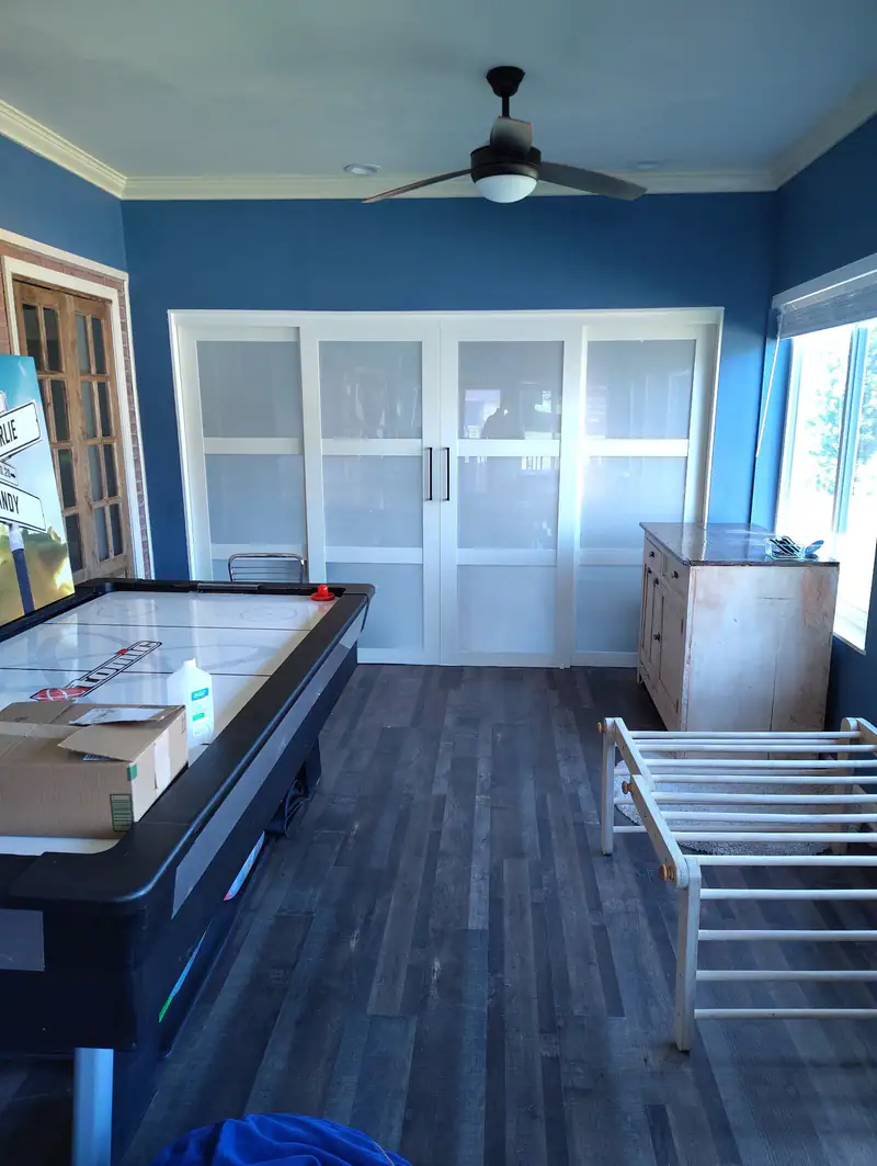 Finished sunroom with blue walls, a ceiling fan and frosted sliding doors